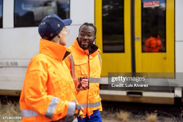 two railway workers in reflective vests discussing work outdoors at the shunting yard - train engineer stock pictures, royalty-free photos & images