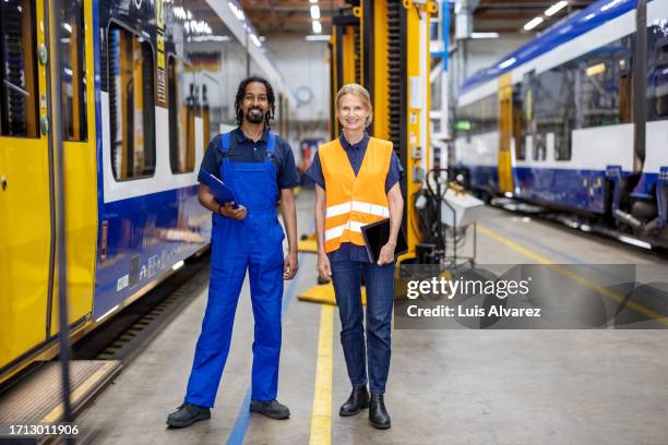 full length portrait of two railway workshop employees standing together - machinist stockfoto's en -beelden