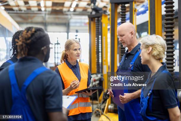 senior manager discussing list of work on digital tablet with team of train maintenance engineers - handwerk alt stock-fotos und bilder