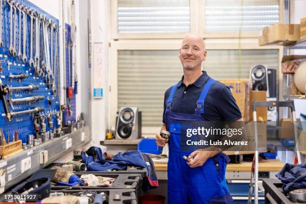 portrait of happy mature engineer standing in railway maintenance workshop - lokführer stock-fotos und bilder