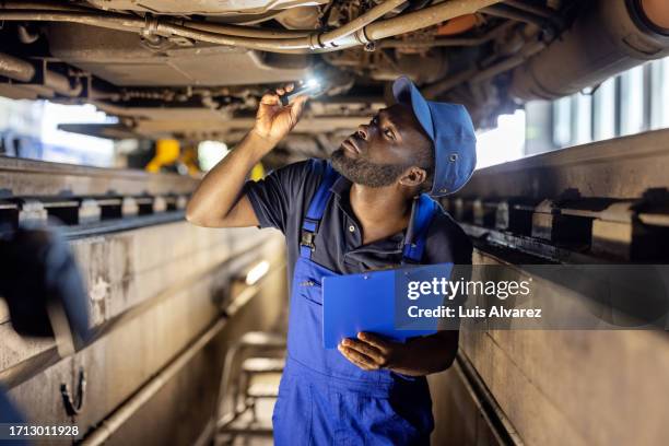 maintenance engineer conducts a check of the train components undercarriage with a flashlight - lokführer stock-fotos und bilder