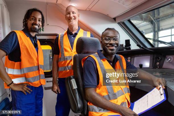 portrait of three train maintenance engineers in train driver cabin - lokführer stock-fotos und bilder