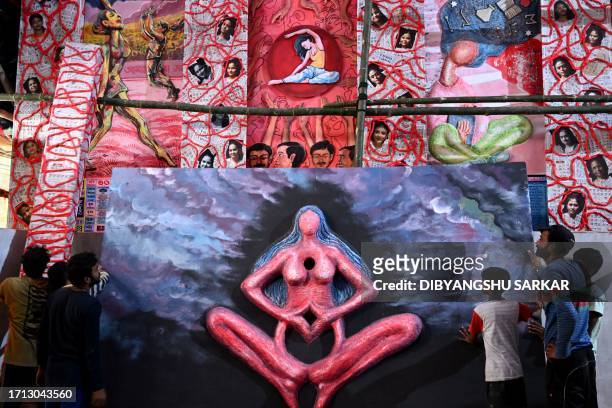 People install an art work at a Pandal with a theme on menstrual hygiene, in Kolkata on October 8, 2023.