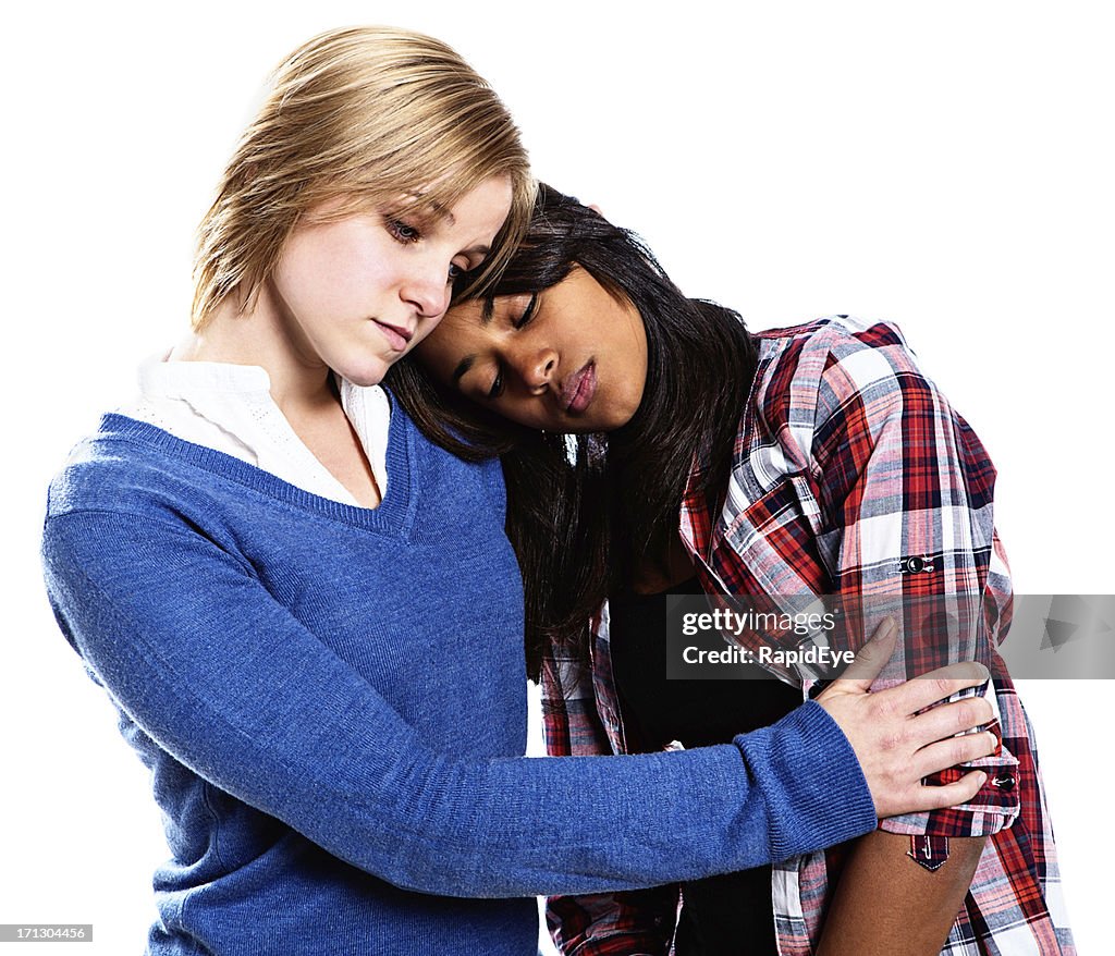 Two unhappy-looking young women console each other