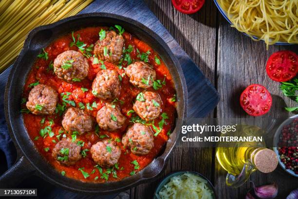 espaguetis con albóndigas con salsa de tomate casero en sartén rústica de hierro fundido sobre madera - meatball fotografías e imágenes de stock