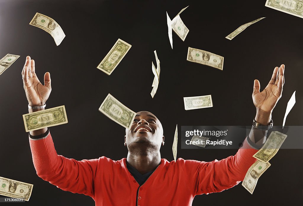 Happy man is showered in dollar bills