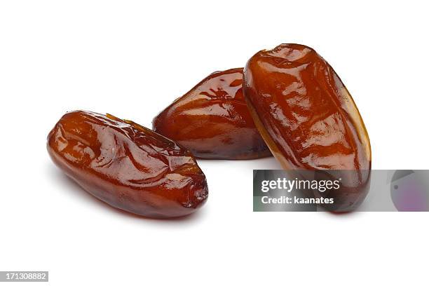 three dried dates laying on a white surface - date stockfoto's en -beelden