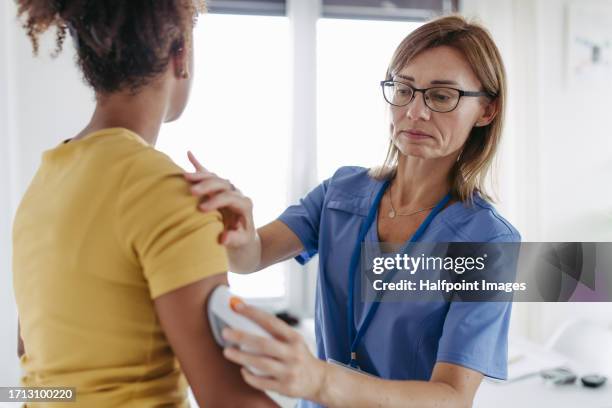 diabetologist applying a continuous glucose monitor sensor to the patient's arm. - diabetes symptoms stock pictures, royalty-free photos & images