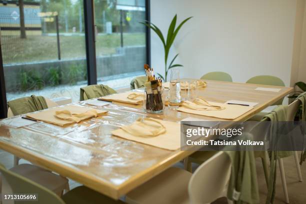 photo of table with beige shopping bags and brushes neatly arranged for art master class - brightly lit classroom stock pictures, royalty-free photos & images