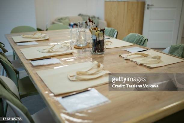 photo of beginning of art master class with empty glasses, brushes, and beige shopping bags on table - brightly lit classroom stock pictures, royalty-free photos & images