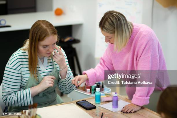 spirited young ginger student eagerly absorbs wisdom of teacher exploring world of acrylics during art class - eagerly painting stockfoto's en -beelden