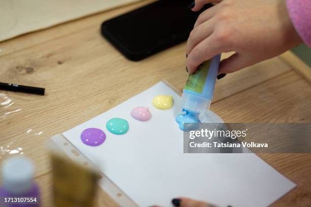 hands of female painter squeezing out acrylic paint on palette to show students how to work with acrylics - brightly lit classroom stock pictures, royalty-free photos & images