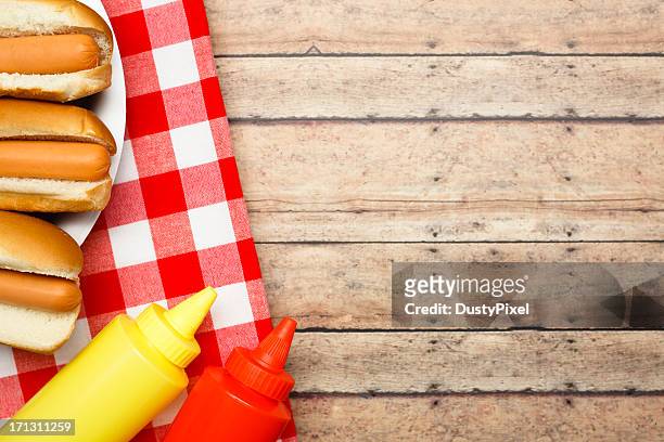 ketchup, mustard and hotdogs on a wooden table - outdoor table stock pictures, royalty-free photos & images