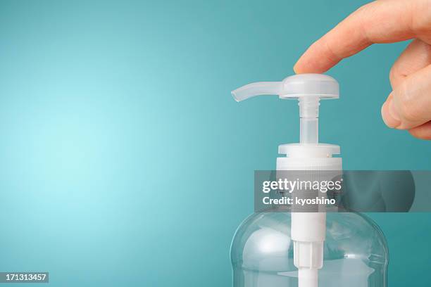 finger pushing the soap dispenser against blue background - soap dispenser stock pictures, royalty-free photos & images