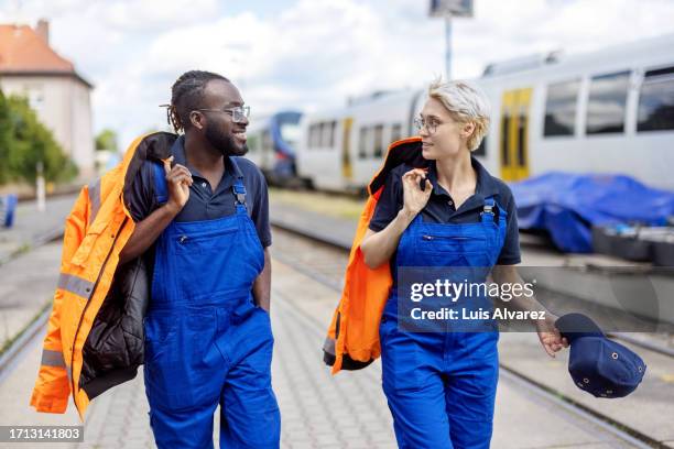 train engineers at railway station walking and talking outside - work overalls stock pictures, royalty-free photos & images