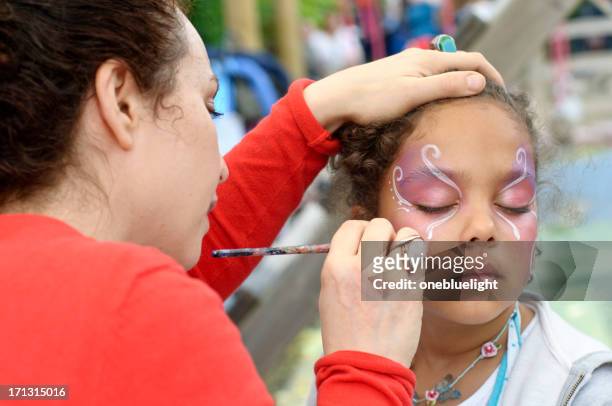 little girl of (6-7) is getting her face paint, outdoors - face paint stock pictures, royalty-free photos & images