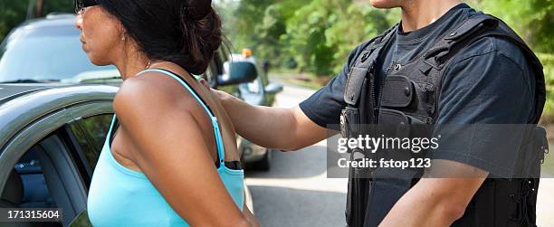policeman putting handcuffs on woman beside vehicles - 被捕 個照片及圖片檔