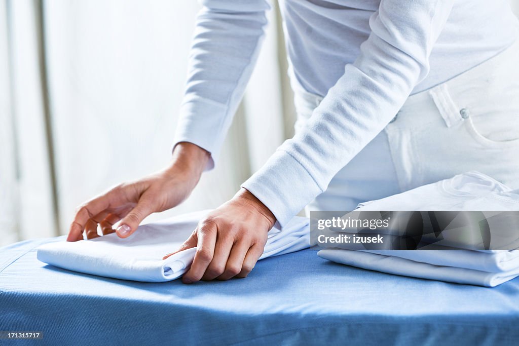 Woman Stacking Ironed Folded Shirts