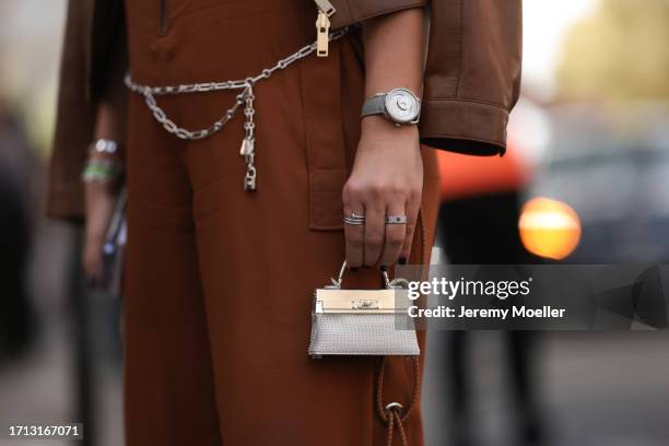 Guest is seen outside Hermes show wearing silver Hermes watch, Hermes Mini Mini Kelly in silver and crystals, white gold Cartier just un clou ring...