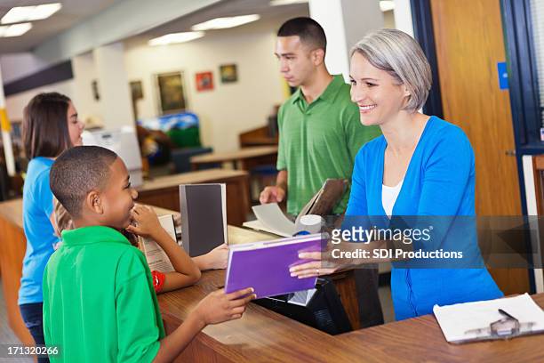 librarian teacher helping students check out books in school library - counter intelligence stock pictures, royalty-free photos & images