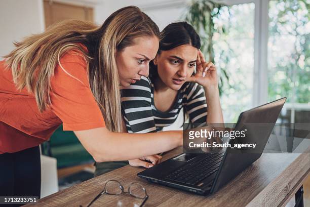 two young woman experiencing online fraud and trying to solve it - tax fraud stock pictures, royalty-free photos & images