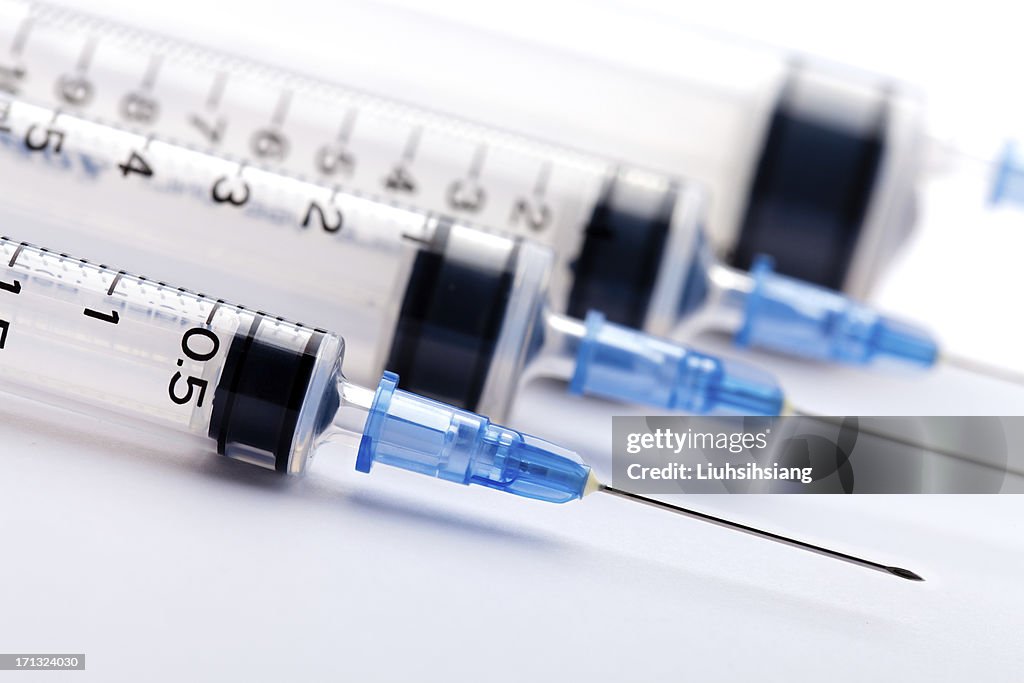 Row of medical syringes with blue lids