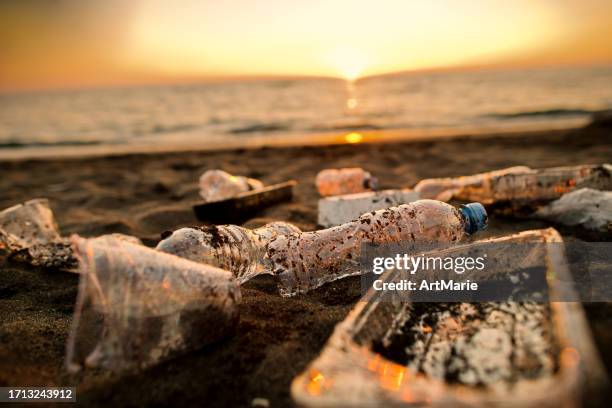 rifiuti di plastica scartati sulla spiaggia al tramonto. concetto di inquinamento ambientale e problemi ecologici. - inquinamento causato dalla plastica foto e immagini stock