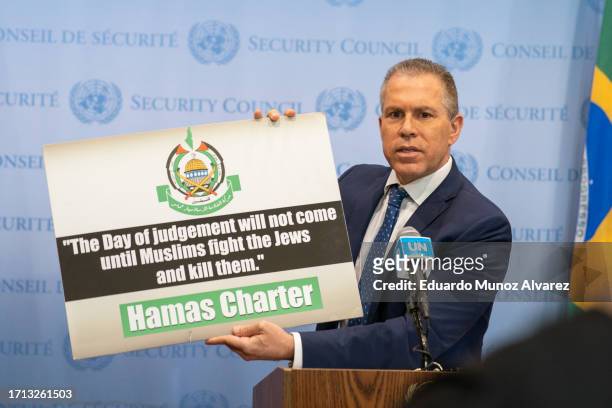 Israel's Ambassador to the U.N. Gilad Erdan holds up a sign as he speaks to reporters during a stakeout before the UN Security Council on October 8,...