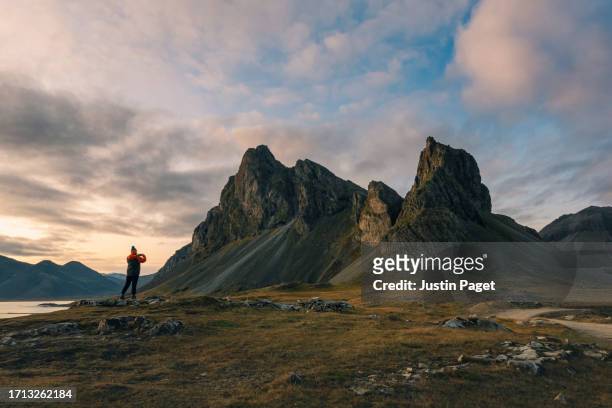 a female tourist takes a photo of a beautiful rock formation at sunset in iceland - 壮大な景観 ストックフォトと画像