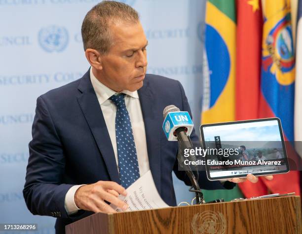 Israel's Ambassador to the U.N. Gilad Erdan holds up a tablet showing people being kidnaped by Hamas members as he speaks to reporters during a...