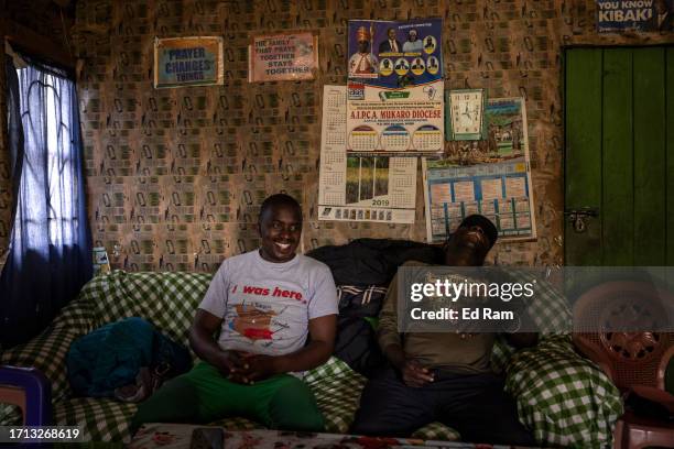 Mountain Guide David Wangari and porter and chef Joseph Kimani share a joke on Johana Machari's sofa at his home in Gitinga Village, where 60% of the...