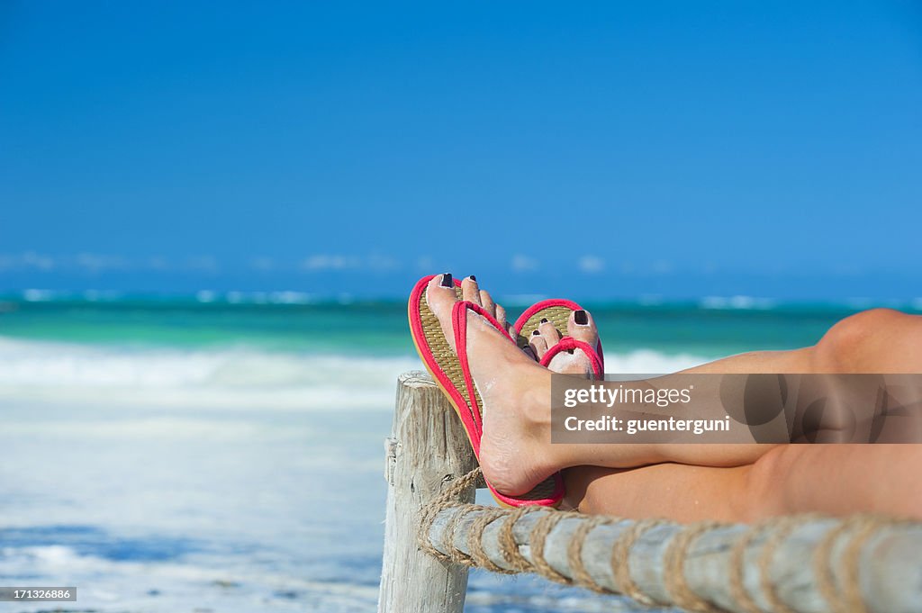 Womans feet with flip-flops at the beach