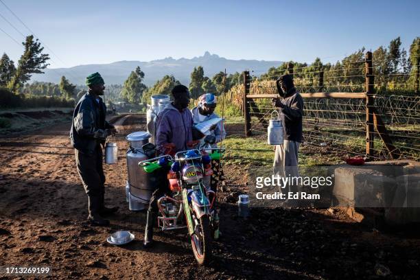 Mount Kenya is silhouetted by early morning sun as men buy milk from a women to sell in the market on September 30, 2023 on the outskirts of Mount...