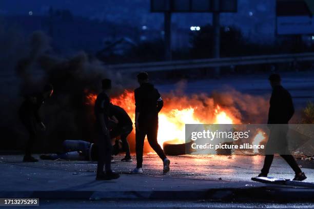 October 2023, Palestinian Territories, Huwara: Palestinians burn tires in front of Israeli security forces during clashes in the West Bank village of...
