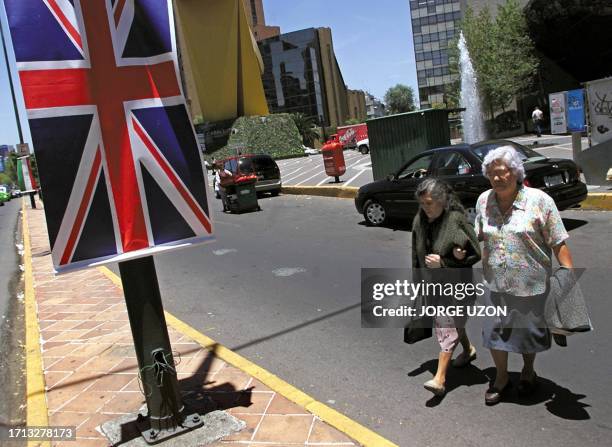 Two women walk next to an English flag in one of the main avenues in Mexico City, 01 August 2001, in preparation for British Prime Minister's visit,...