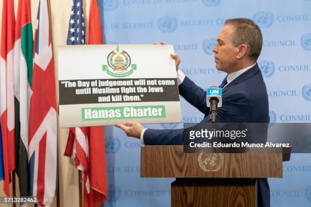 Israel's Ambassador to the U.N. Gilad Erdan holds up a sign as he speaks to reporters during a stakeout before the UN Security Council on October 8,...