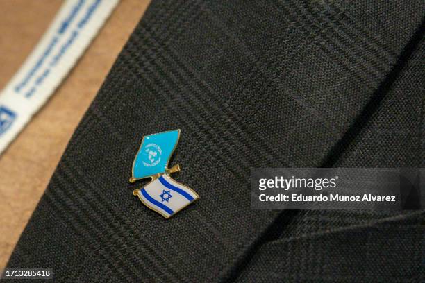 Woman wears a pin with the U.N. Flag and Israel's flag while Israel's Ambassador to the U.N. Gilad Erdan speaks to reporters during a stakeout before...