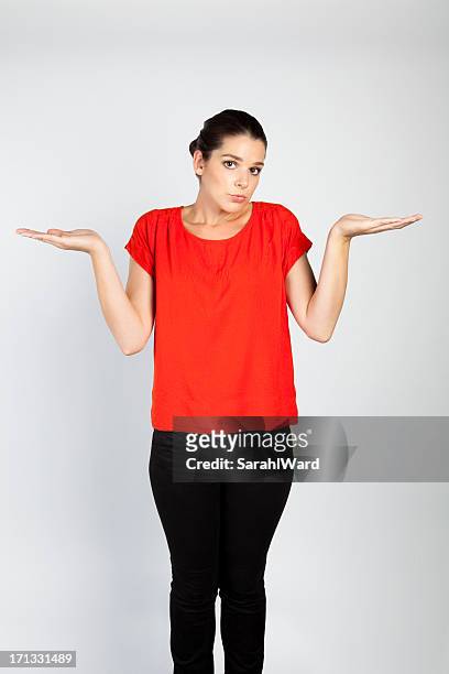 beautiful young woman with confused expression - schouders ophalen stockfoto's en -beelden