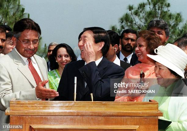 Chinese Prime Minister Zhu Rongji shares a smile with Pakistani military ruler General Pervez Musharraf while signing a visitor's book at a tourist...