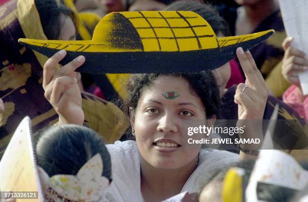 An activist of ruling Awami League of Prime Minister Sheikh Hasina Wajed holds a cutout of boat as she also paint her forehead like a boat, which is...