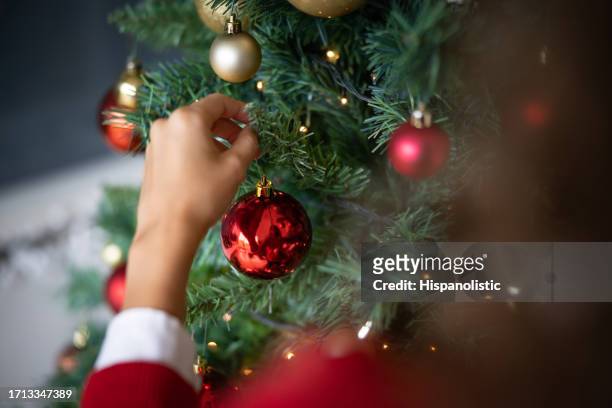 woman decorating the christmas tree - tree trimming stock pictures, royalty-free photos & images