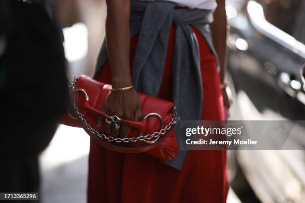 Fashion Week Guest was seen wearing a red skirt, a white T-Shirt, a grey pullover bound on her waist, a red Gucci Horsebit bag as well as a yellow...