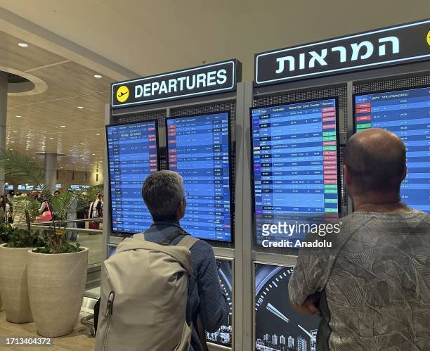 People look at the board showing departure schedules at Ben Gurion Airport, Israel's only international airport, after many flights from abroad are...