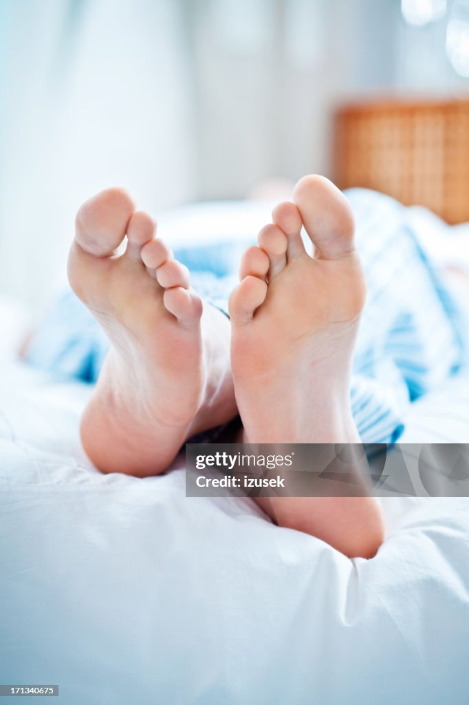 Männliche Füße im Bett