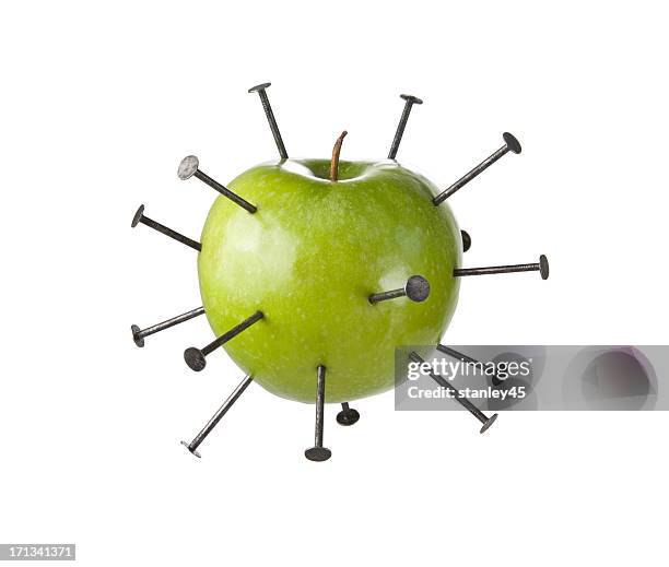 construction nails piercing a green apple - doordringen stockfoto's en -beelden