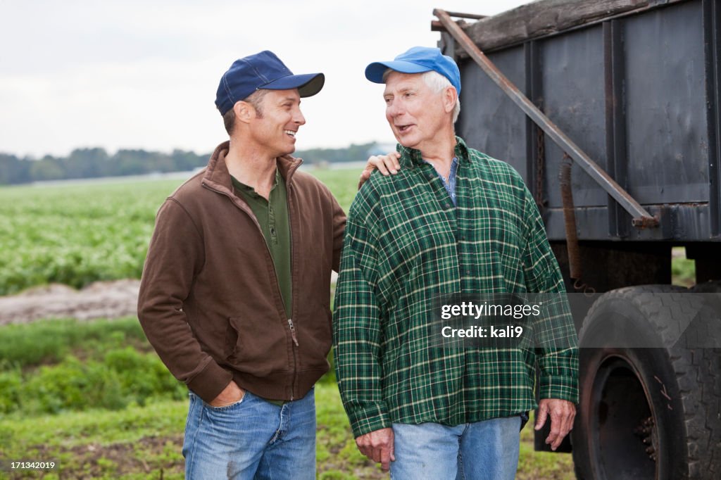 Two men working on a farm, talking by a truck