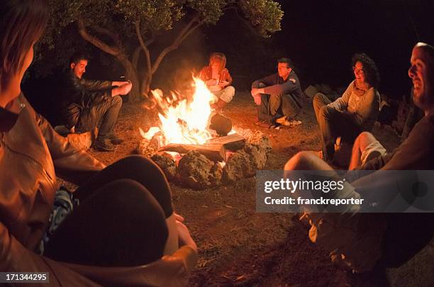 grupo reunidos alrededor de la hoguera en el bosque - fuego al aire libre fotografías e imágenes de stock