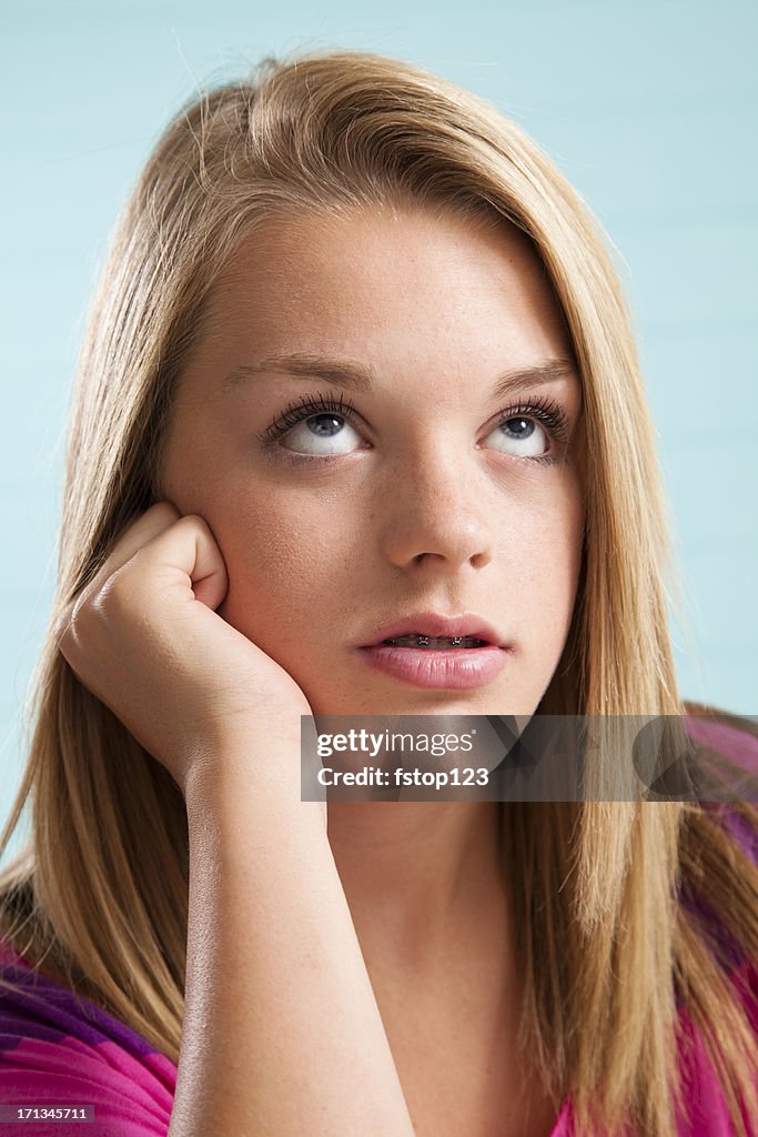 Lovely blonde teenage girl rolling her eyes upward.