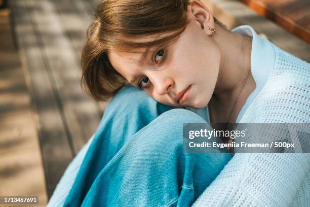 a teenage girl sits on a bench on the street,hugging her knees - vulnerabilità foto e immagini stock