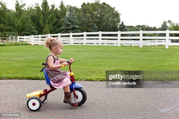 girl in dress & cowboy boots riding tricycle - tricycle stock pictures, royalty-free photos & images